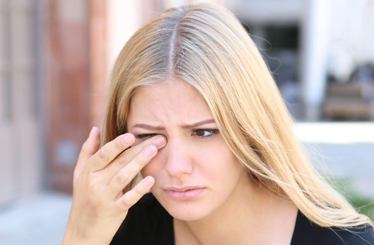 Woman rubbing irritated eye — dry eye symptoms